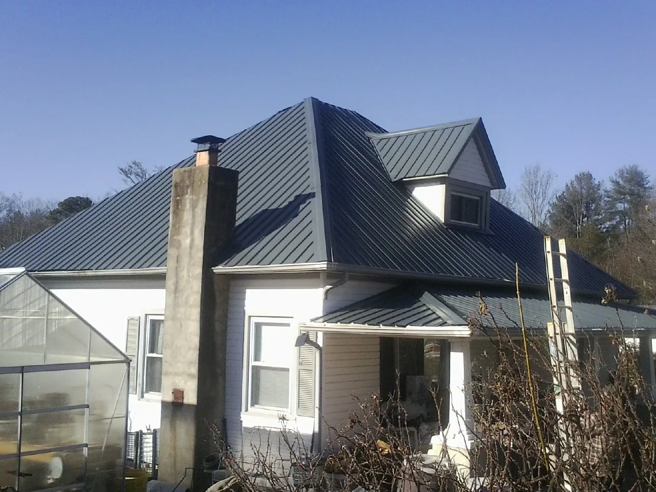 Dark blue standing seam metal roof on a white farmhouse with dormer — Slate & Tile Roof Repair by Roofing Brothers in Herald