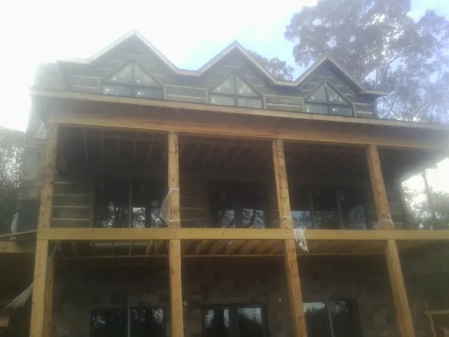 Dormers and porch framing on a large log home under construction — Roof Coating work by our crew in Herald