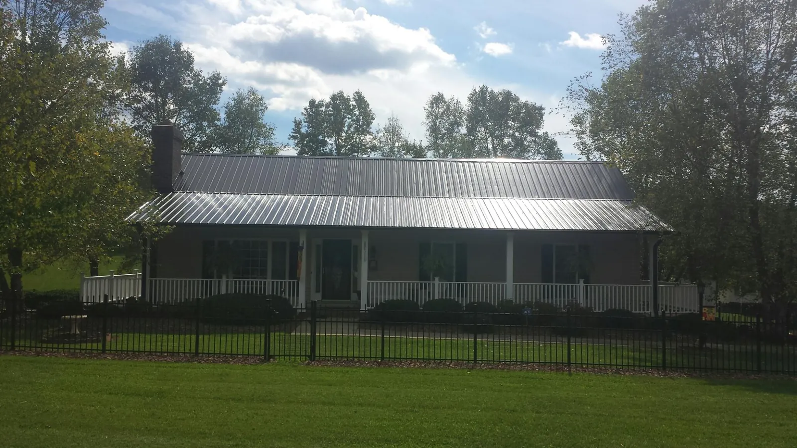 Gray metal roof on a brick ranch with a full width front porch — Gutter Guard Installation work by our crew in Herald